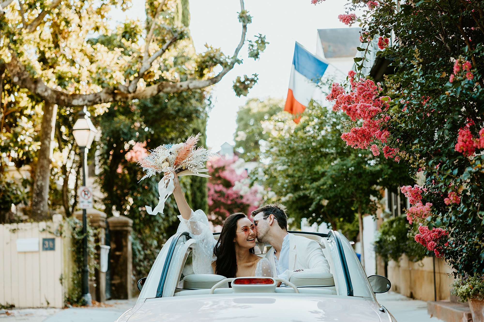 Couple sits together in The Pink Figgy car among an alley in downtown Charleston SC. They are going to elope at the beach.