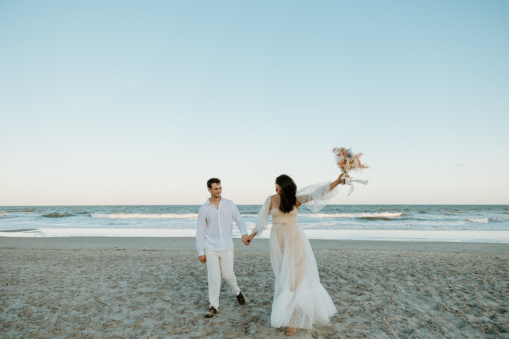 Couple celebrates being married on the beach at sunset in Charleston