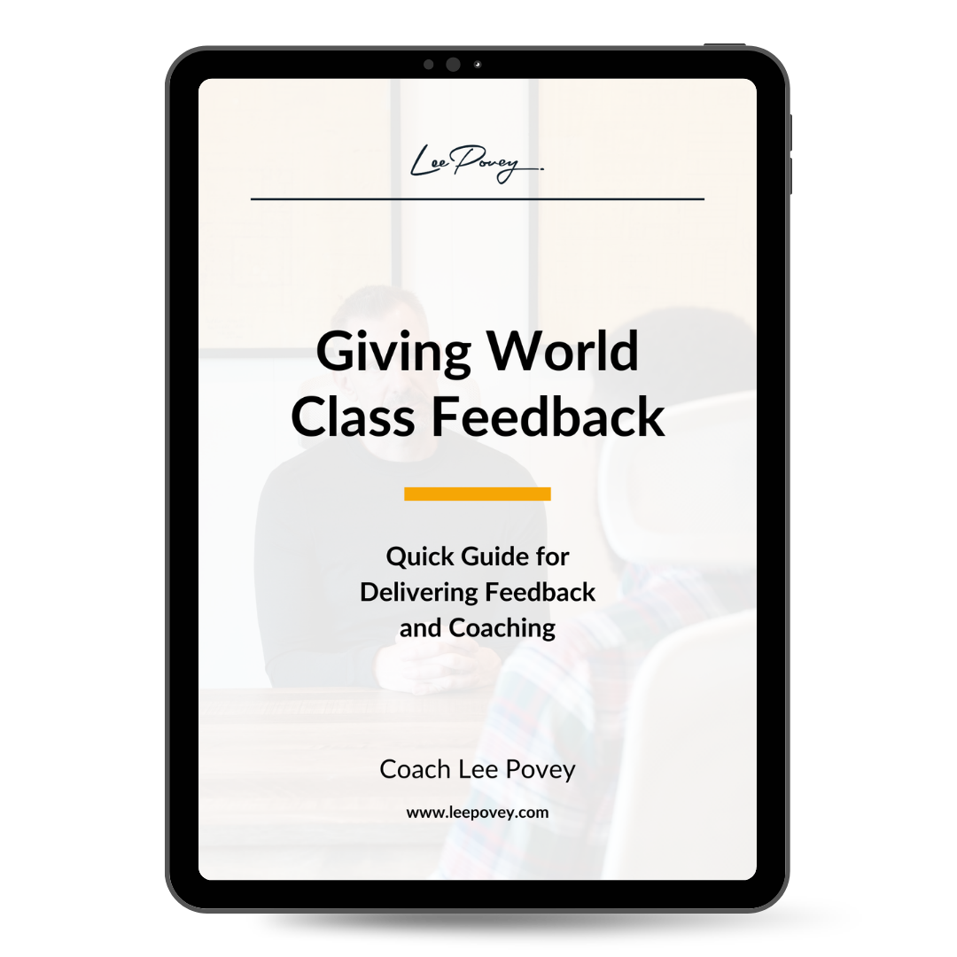 Cover of a guide titled 'Giving World Class Feedback,' by Coach Lee Povey, with a blurred background of two people in a classroom or office setting.
