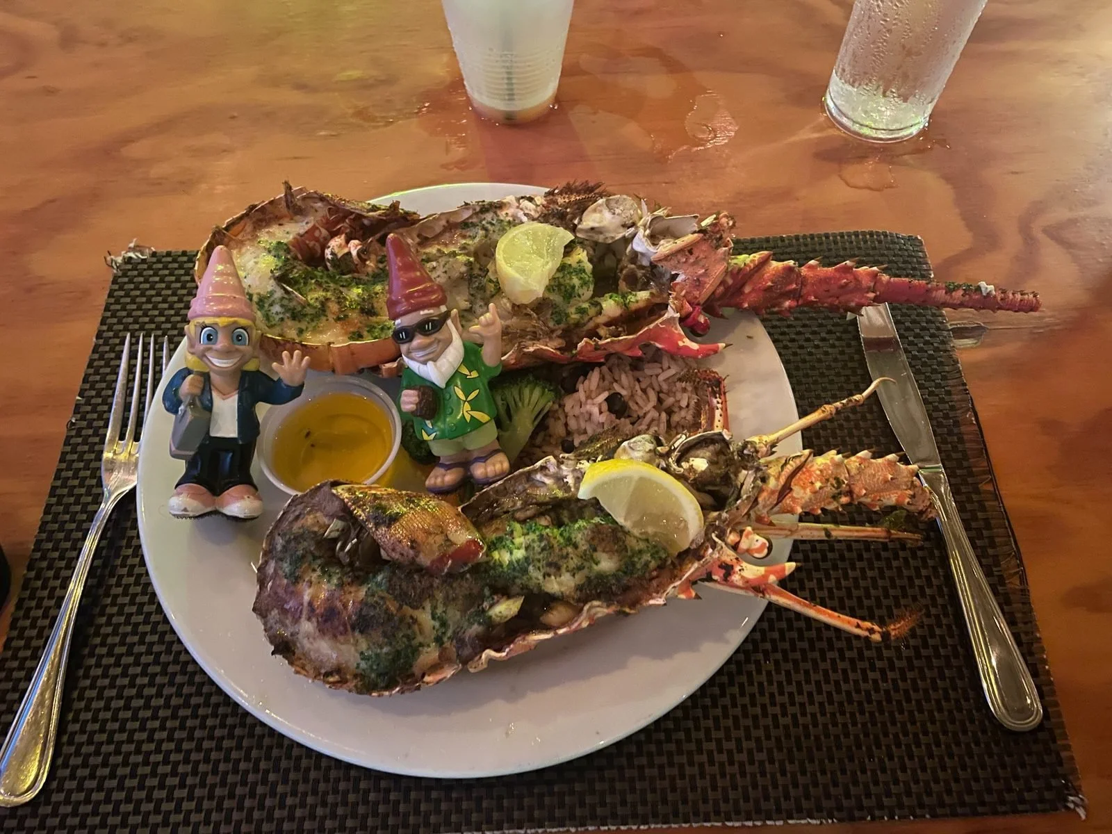 Seafood platter with lobster, fish, and shrimp served with lemon wedges, rice, and dipping sauces, decorated with figurines and cutlery.