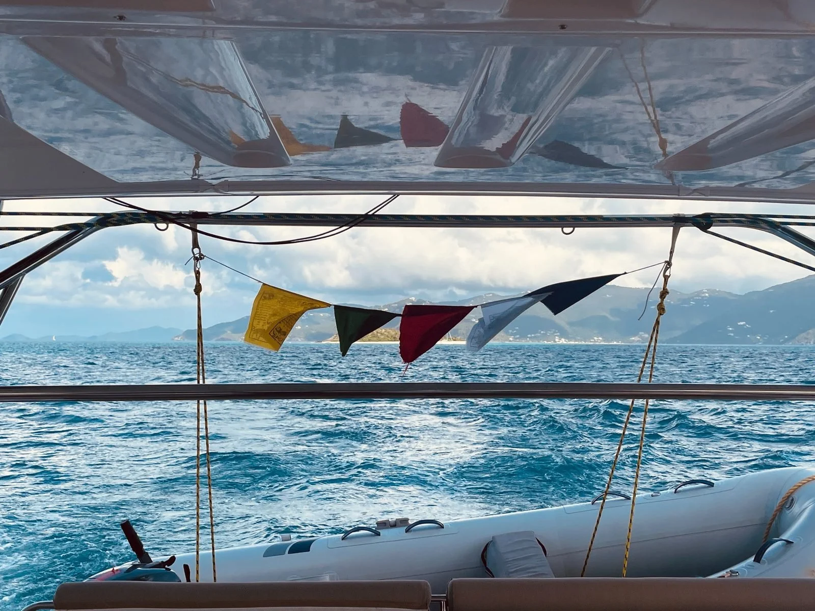 Photo taken from a boat showing water, mountains in the background, and colorful triangular flags hanging above.