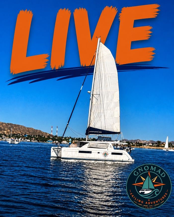A sailboat on calm blue water with a mountain and clear sky background. The sailboat has white sails and the word 'LEOPARD 40' on the boom. Large orange text at the top reads 'LIVE'. A circular logo at the bottom right corner says 'GNOMAD SAILING ADVENTURES' with a sailboat graphic.