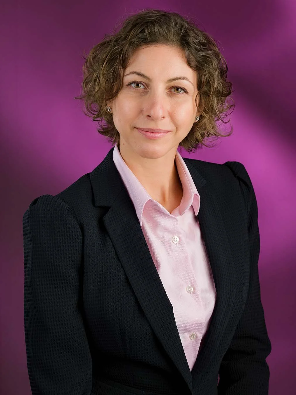 Professional personal branding portrait of a woman in a dark jacket against a magenta studio background