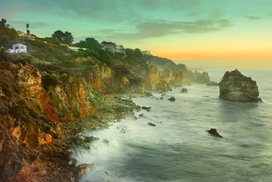 Rocky Algarve coastline at sunrise with sea stacks and waves