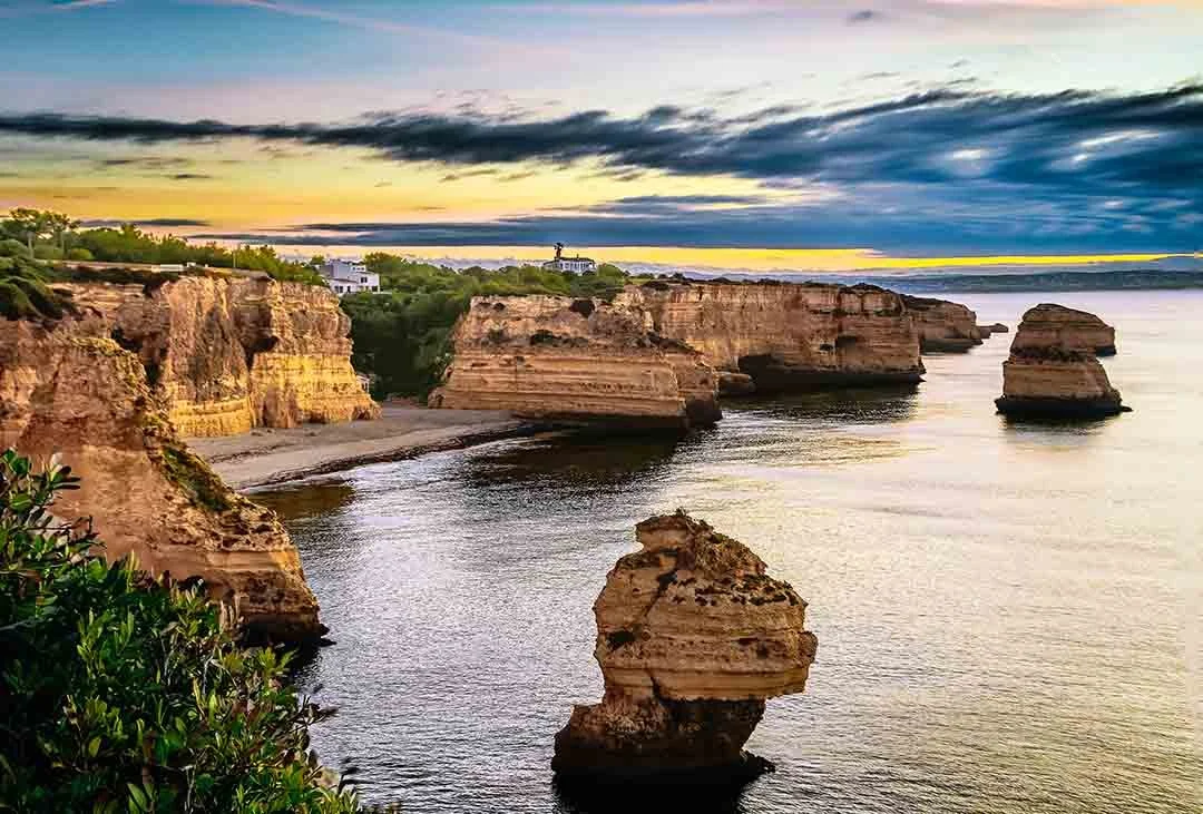 Golden limestone cliffs and sea stacks at Praia da Marinha under a colourful evening sky