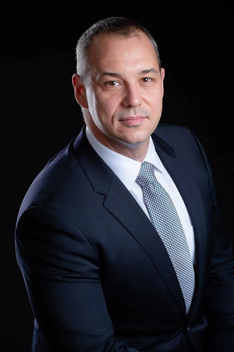 Corporate headshot of a man in a navy suit and tie, photographed in studio in the Algarve