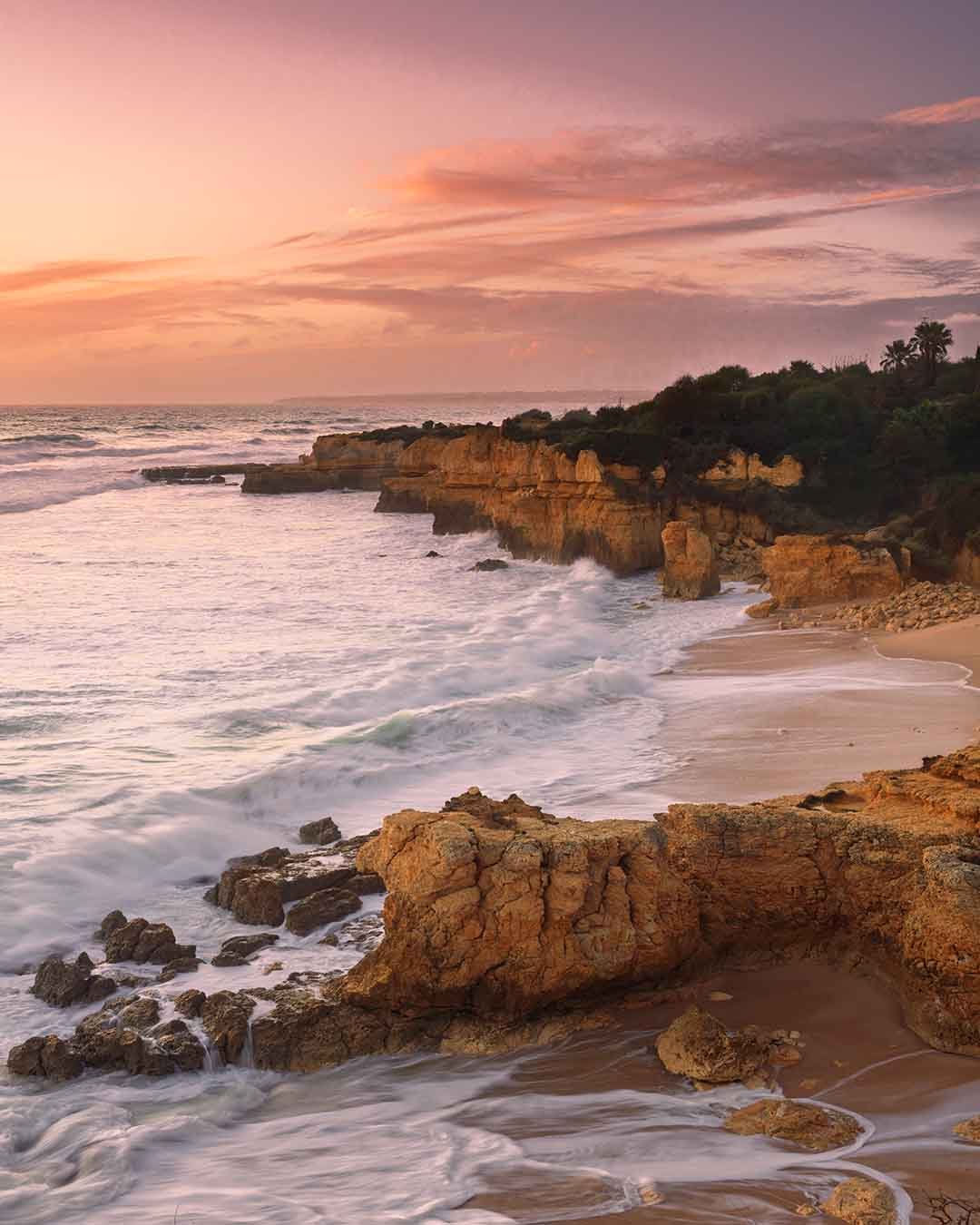 Rocky central Algarve coastline and beach illuminated by warm sunset light