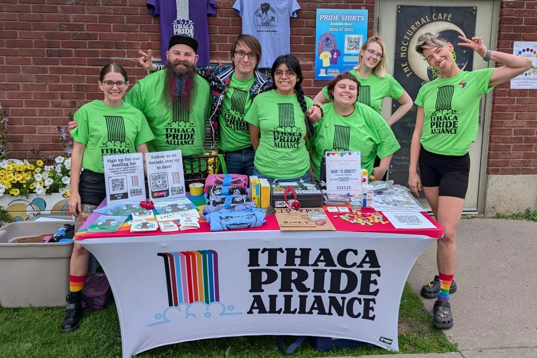 A group of volunteers pose in front of a rainbow table