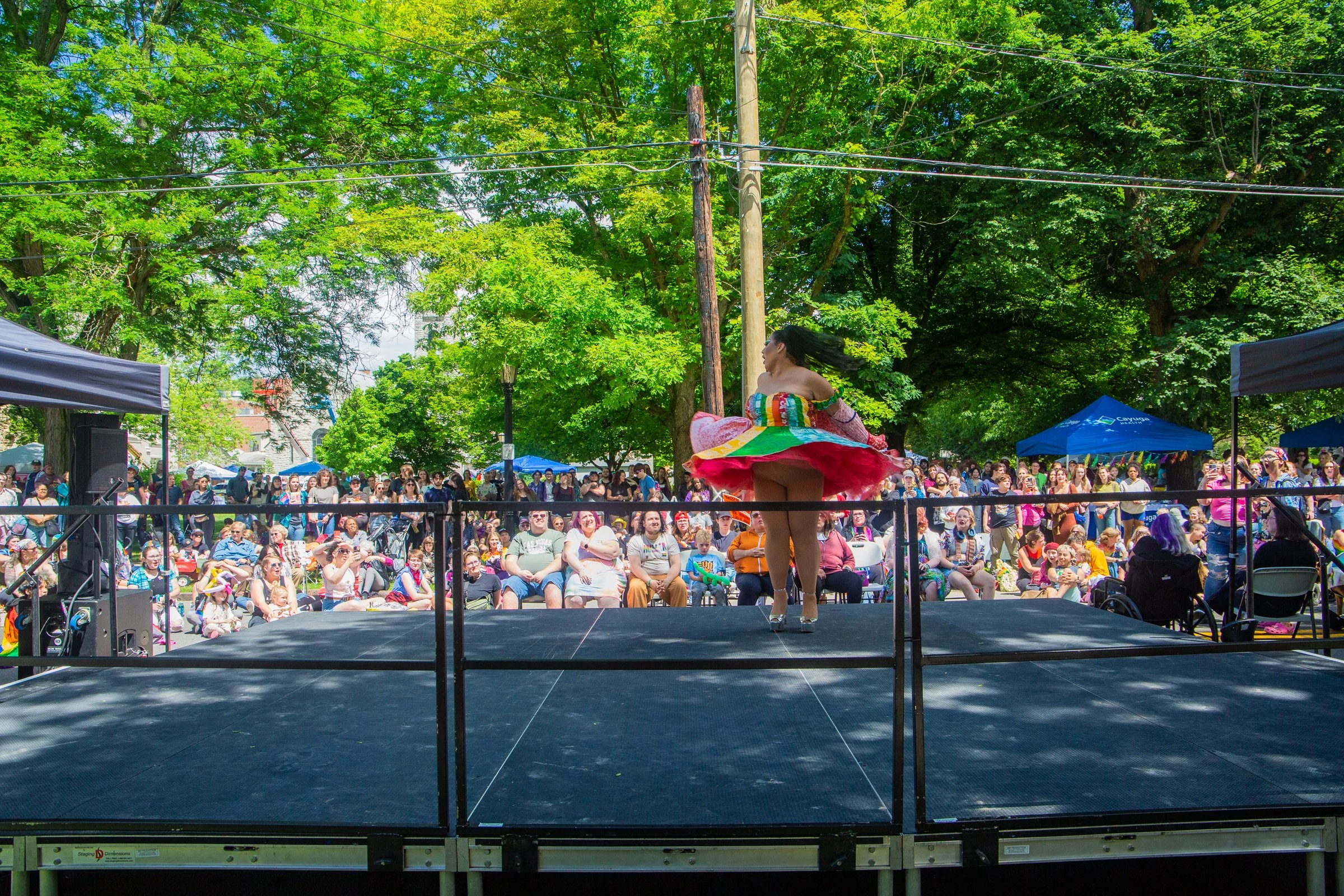 A large crowd watches a performer in a rainbow tutu twirling on stage