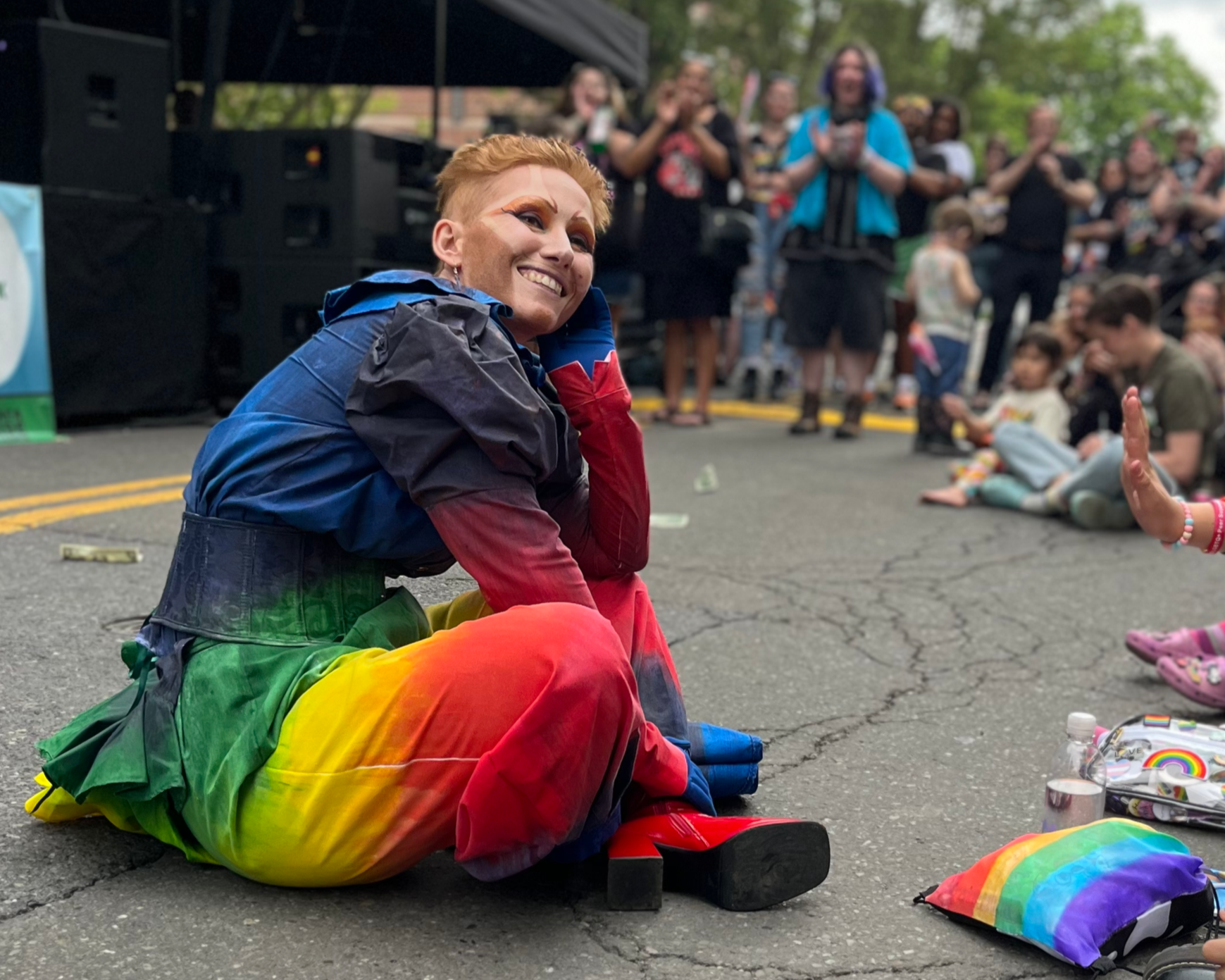 A performer in drag smiles at a crowd of children