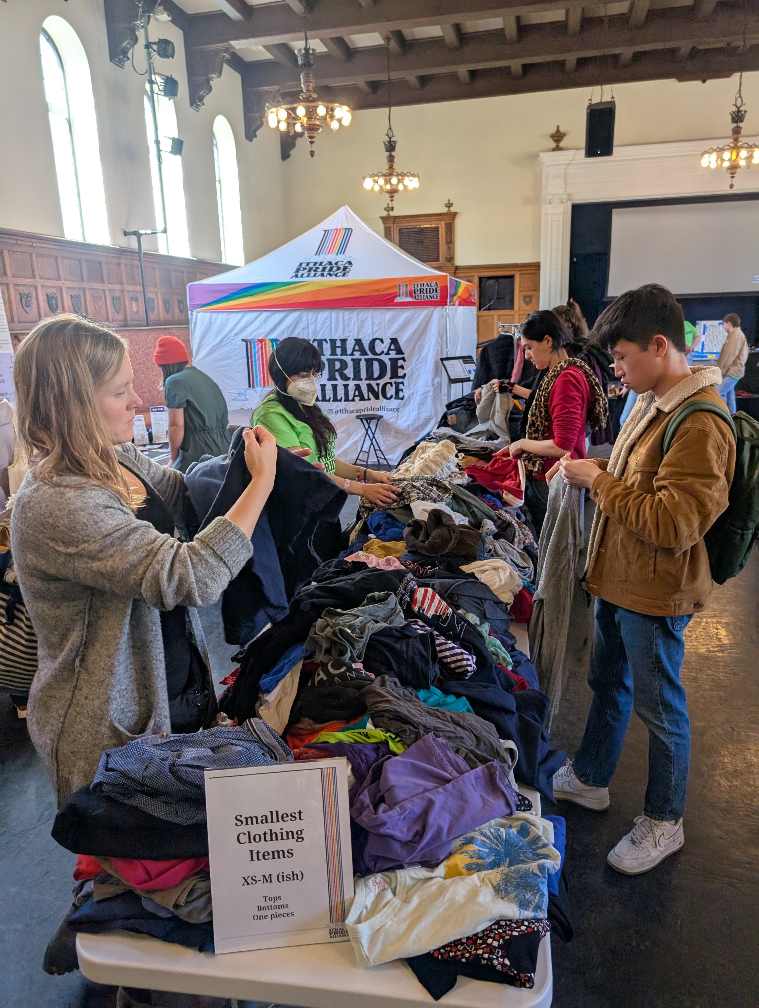Many people pick up items of clothing at a large table piled with free items