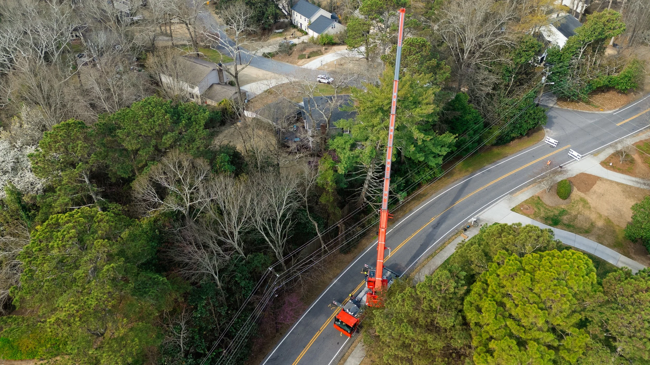Aerial view of Beasley Tree Experts 110-ton Liebherr crane reaching over residential trees in Cherokee County, Georgia