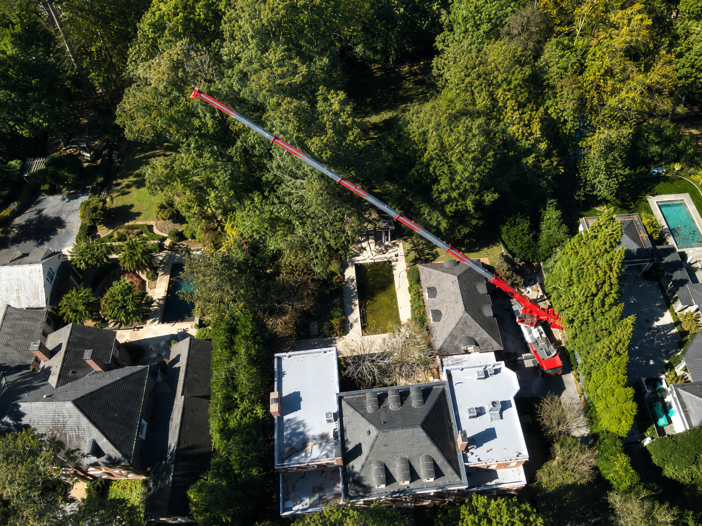 110-ton crane extended over a residential neighborhood with pool during tree removal