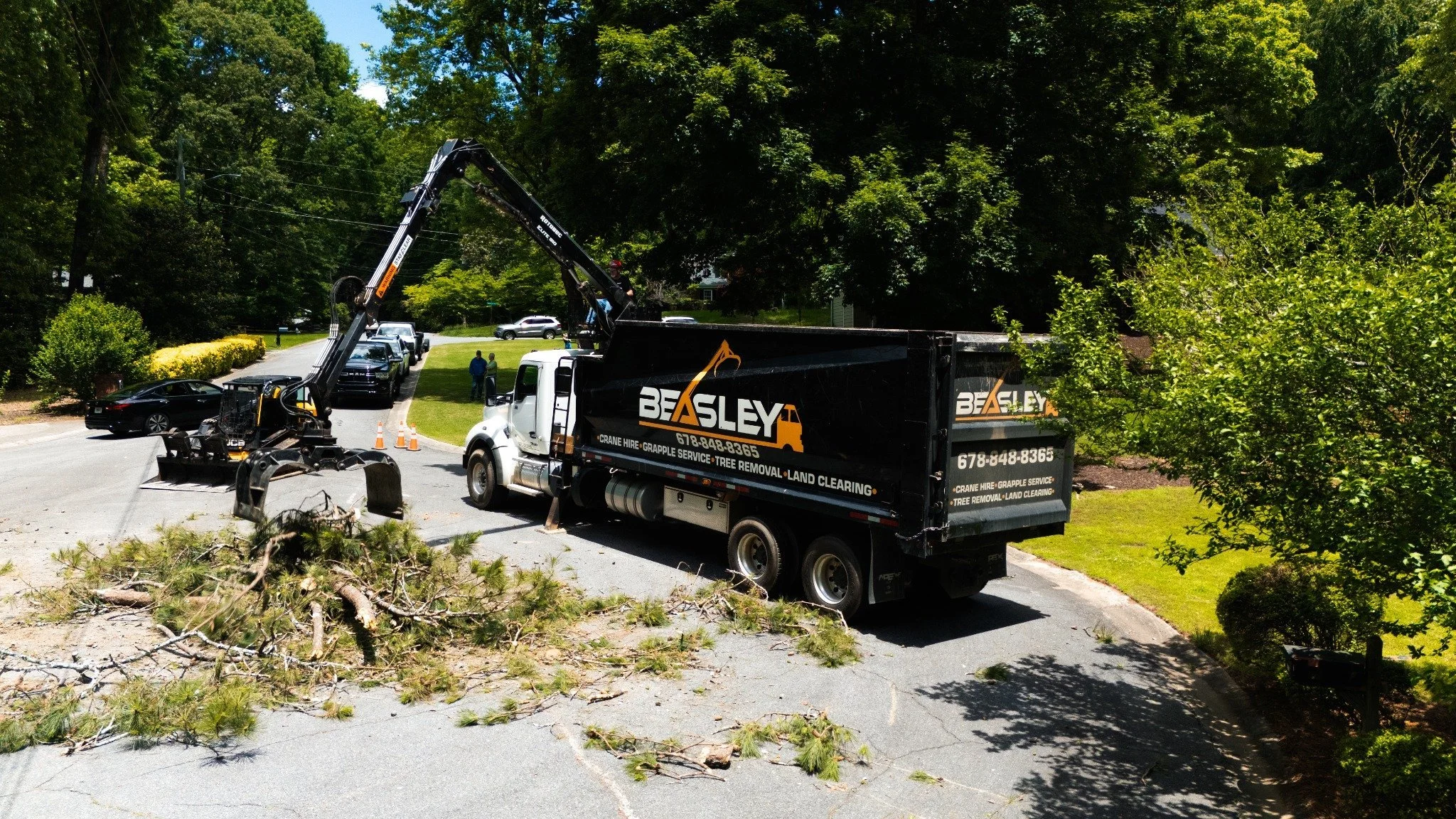 Beasley grapple truck loading debris on a residential street