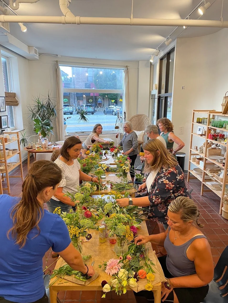 A group of people gathers around a table arranging flowers