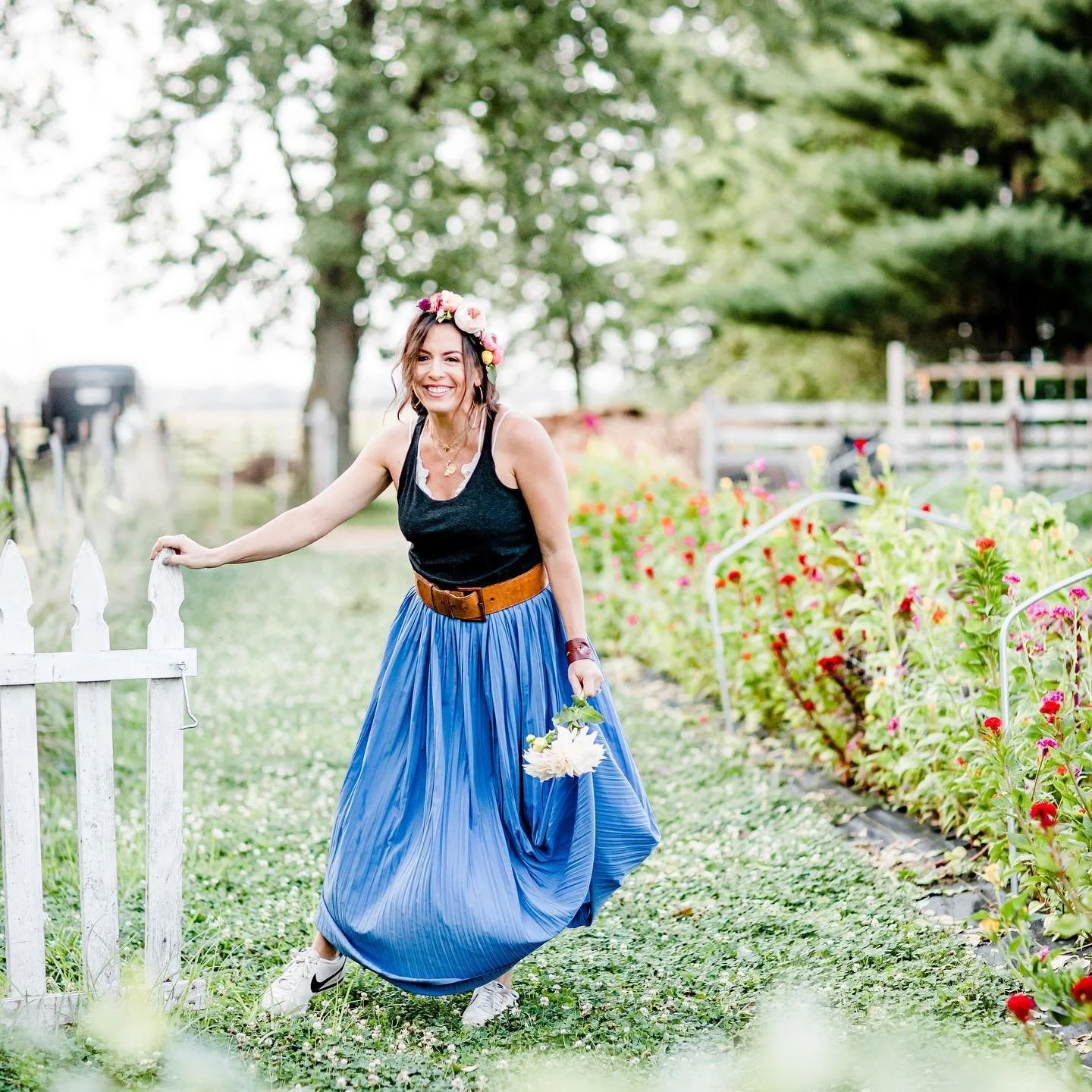 A woman smiles while holding a large flower