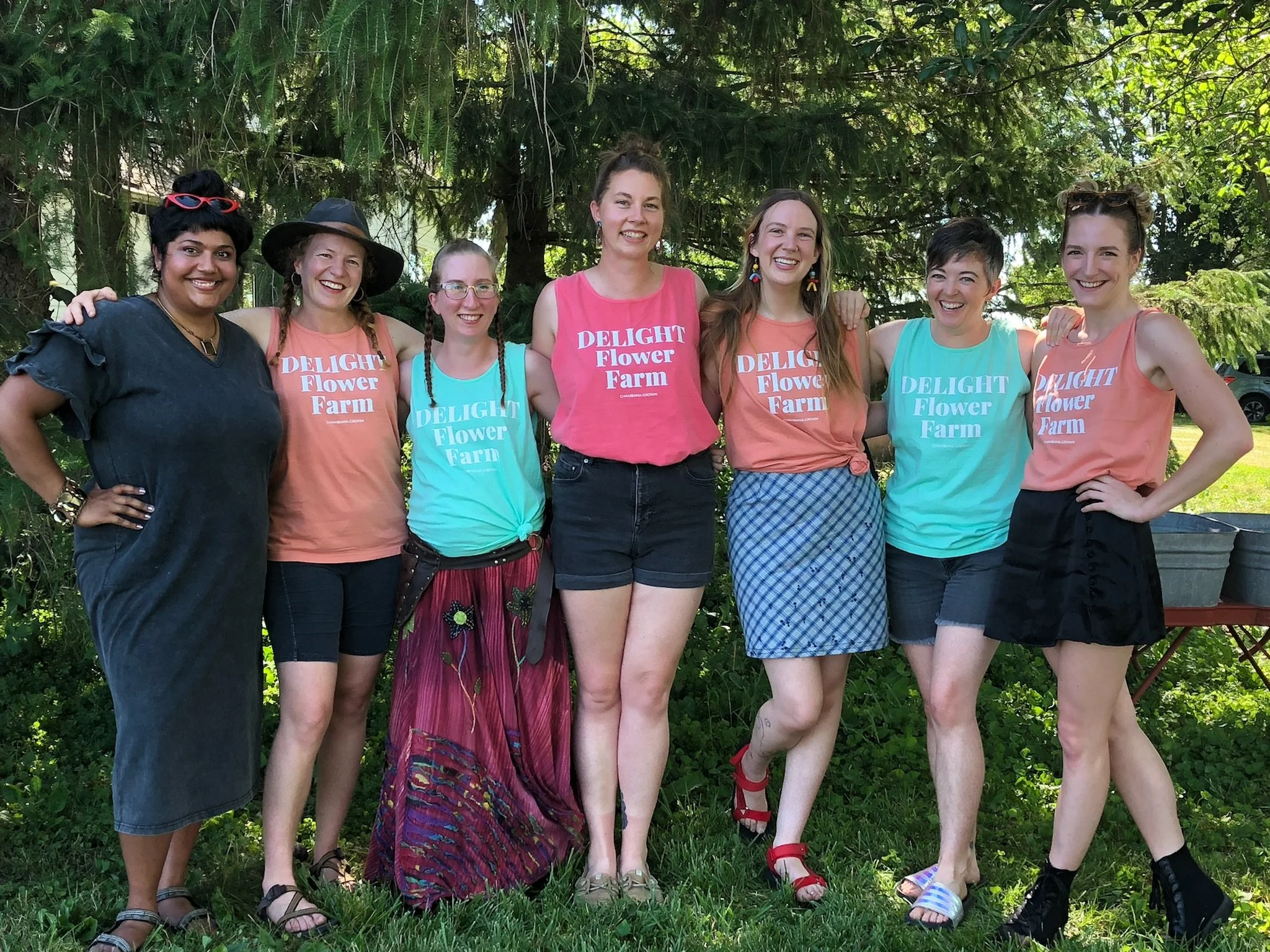 A group of people stand and smile in matching Delight Flower Farm shirts.