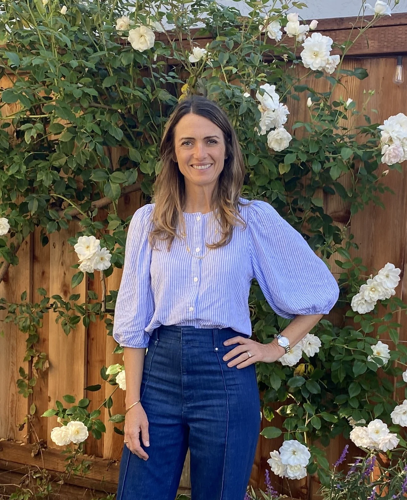 Priscillia de Muizon standing in front of white rose bush
