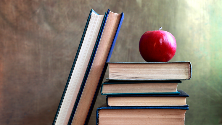 A stack of books with a red apple on top