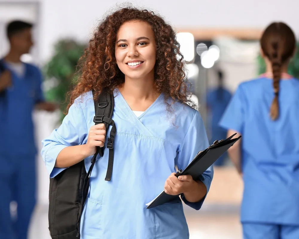 A smiling healthcare student holding a clipboard