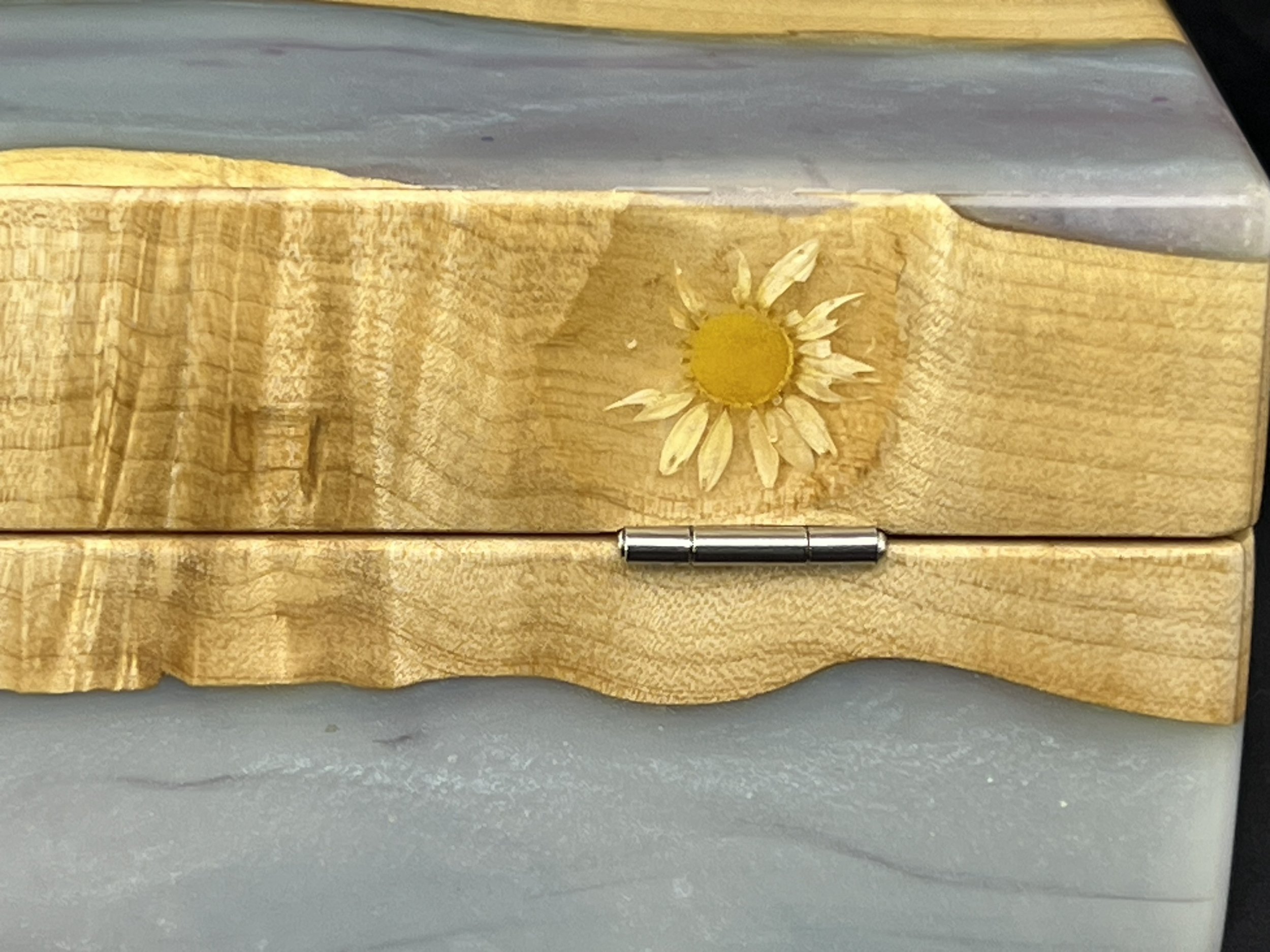 A wooden surface with a small painted daisy flower on it. The surface appears to be a piece of furniture or decor item.
