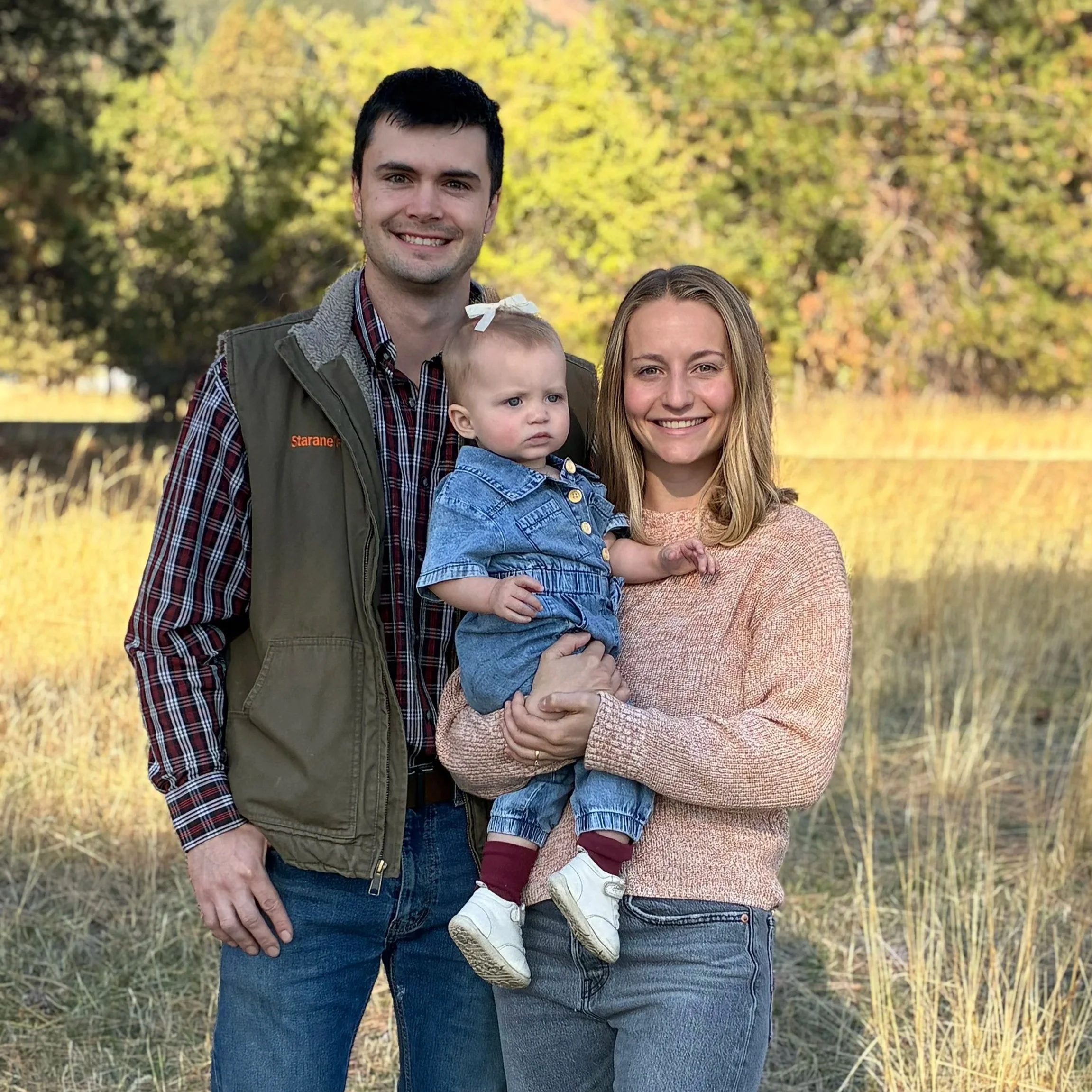 Dr. Lewis Wright with his family outdoors during fall, smiling and posing for a photo, surrounded by trees with yellow leaves.
