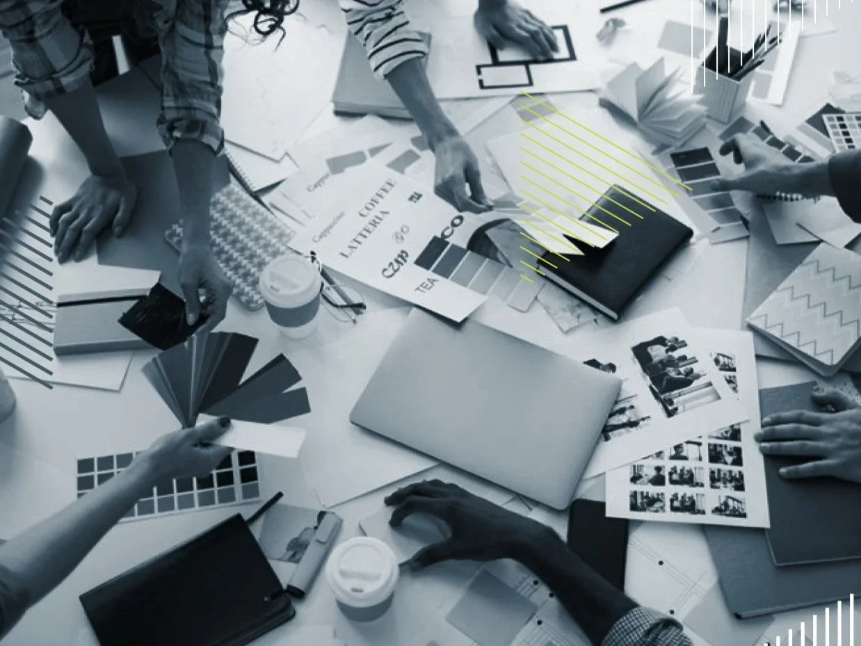 High angle closeup of creative business team working on design project focus on table with photographs and color swatches scattered around