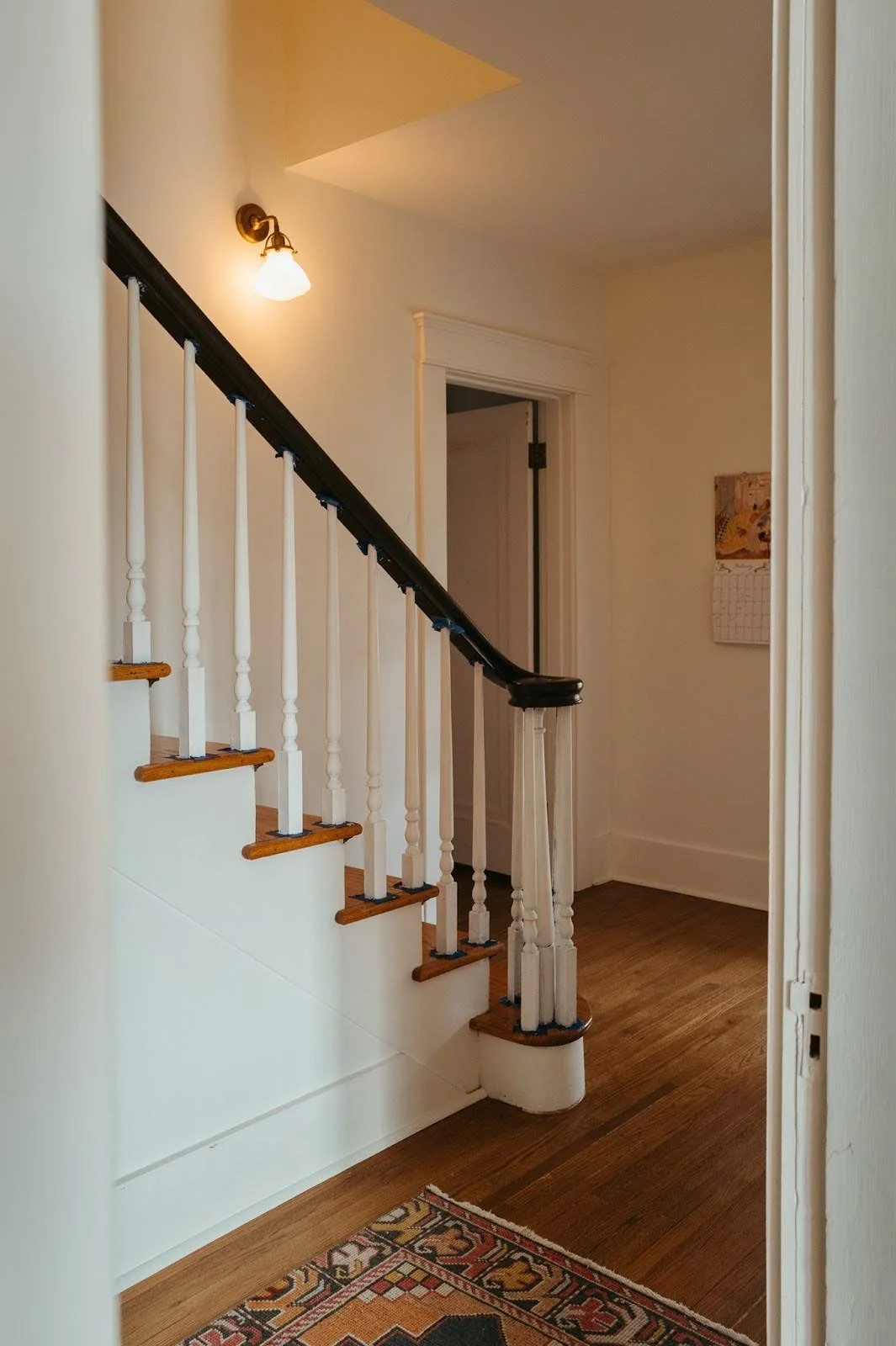 Interior hallway with staircase railing, warm wood floors and soft lighting, showcasing classic residential architecture