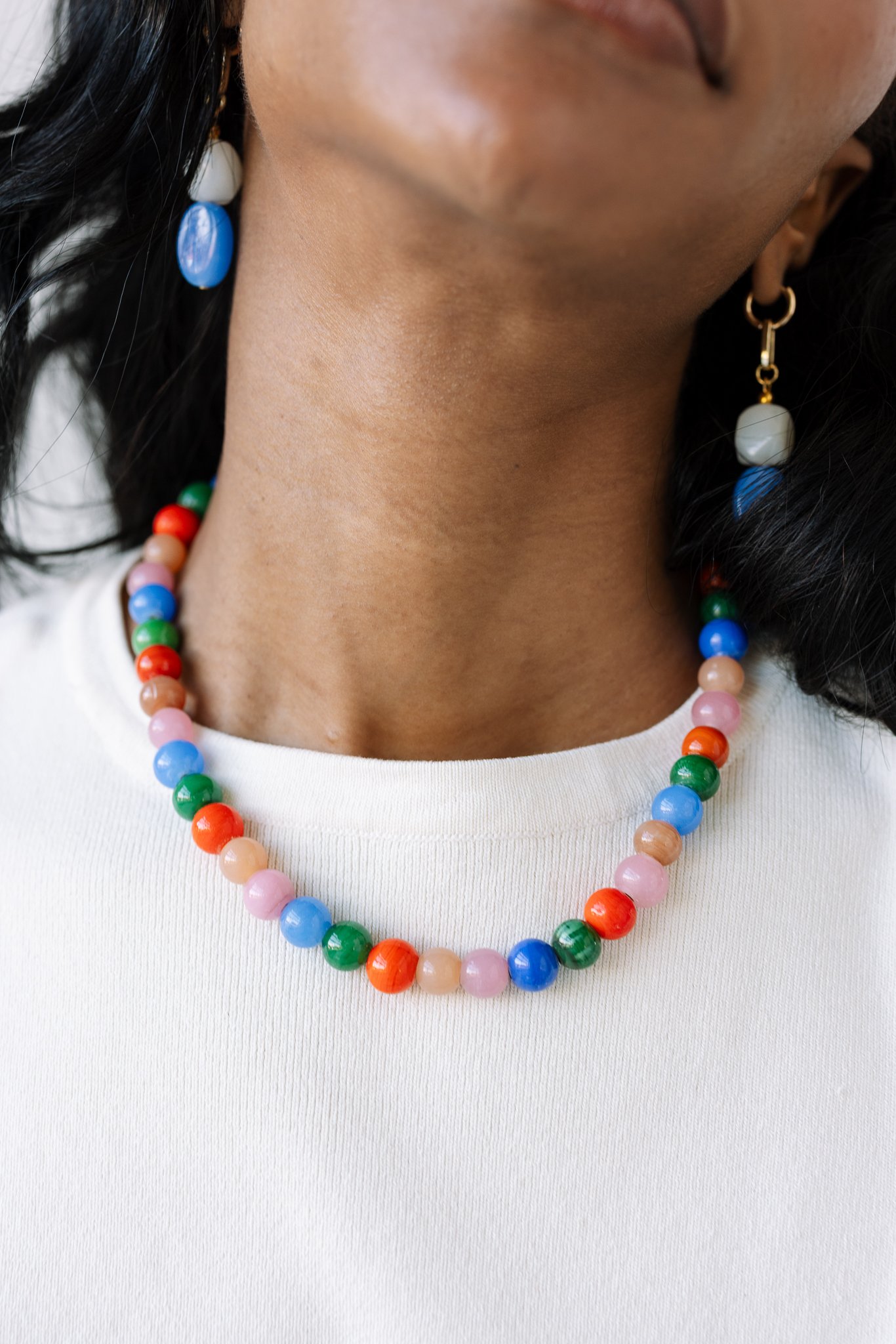 Close-up of person wearing a colorful beaded necklace and earrings.