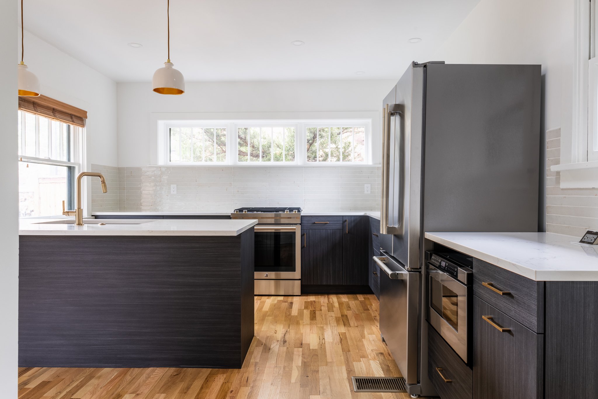 Modern kitchen with stainless steel appliances, wooden flooring, and dark cabinets