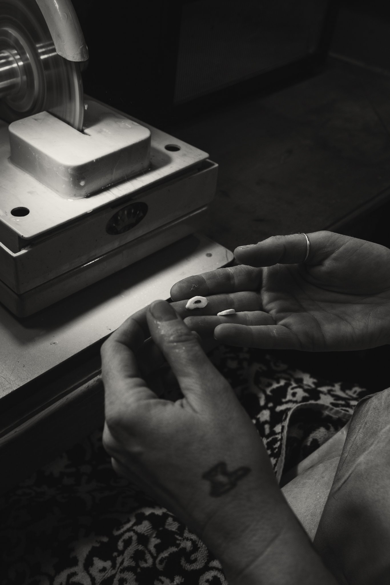 Hands holding small rings near a polishing machine.