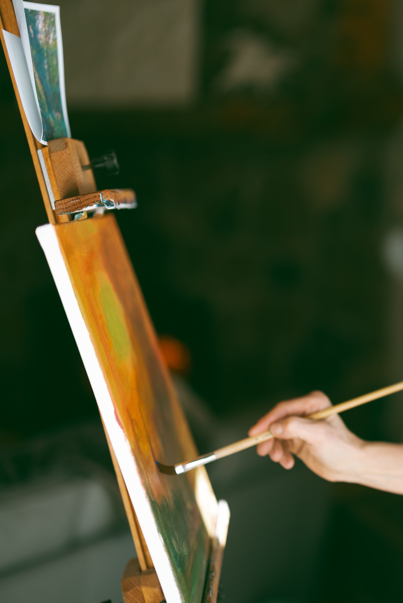 Person painting on canvas using an easel