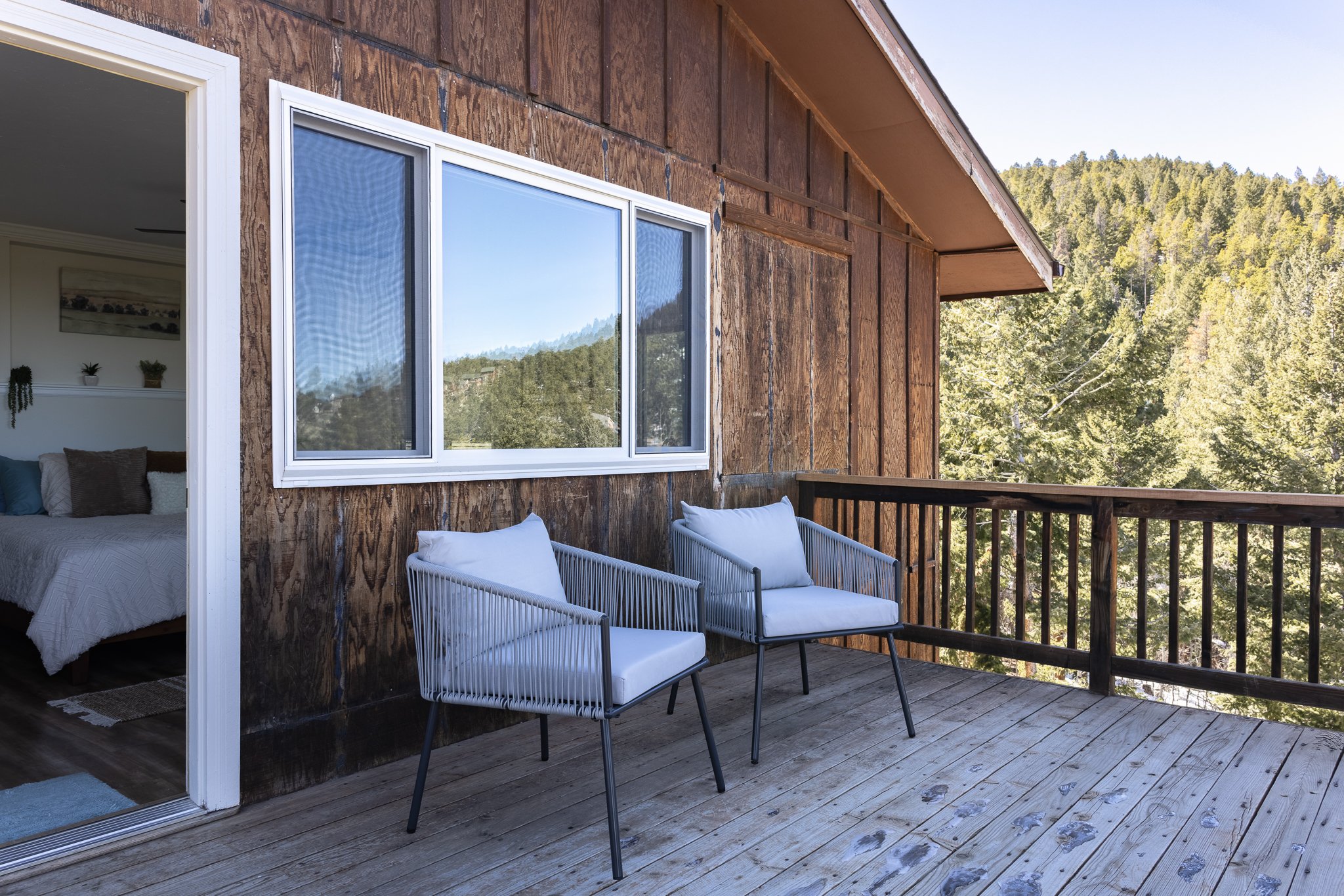 Wooden deck with two cushioned chairs and mountain view