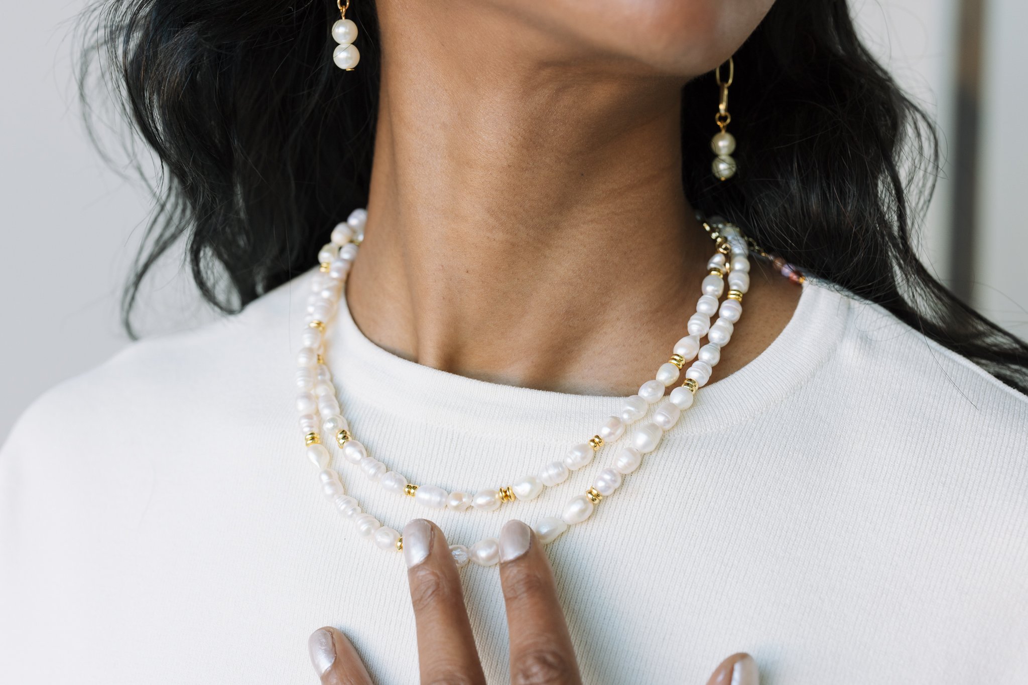 Close-up of a person wearing pearl necklaces and matching pearl earrings.
