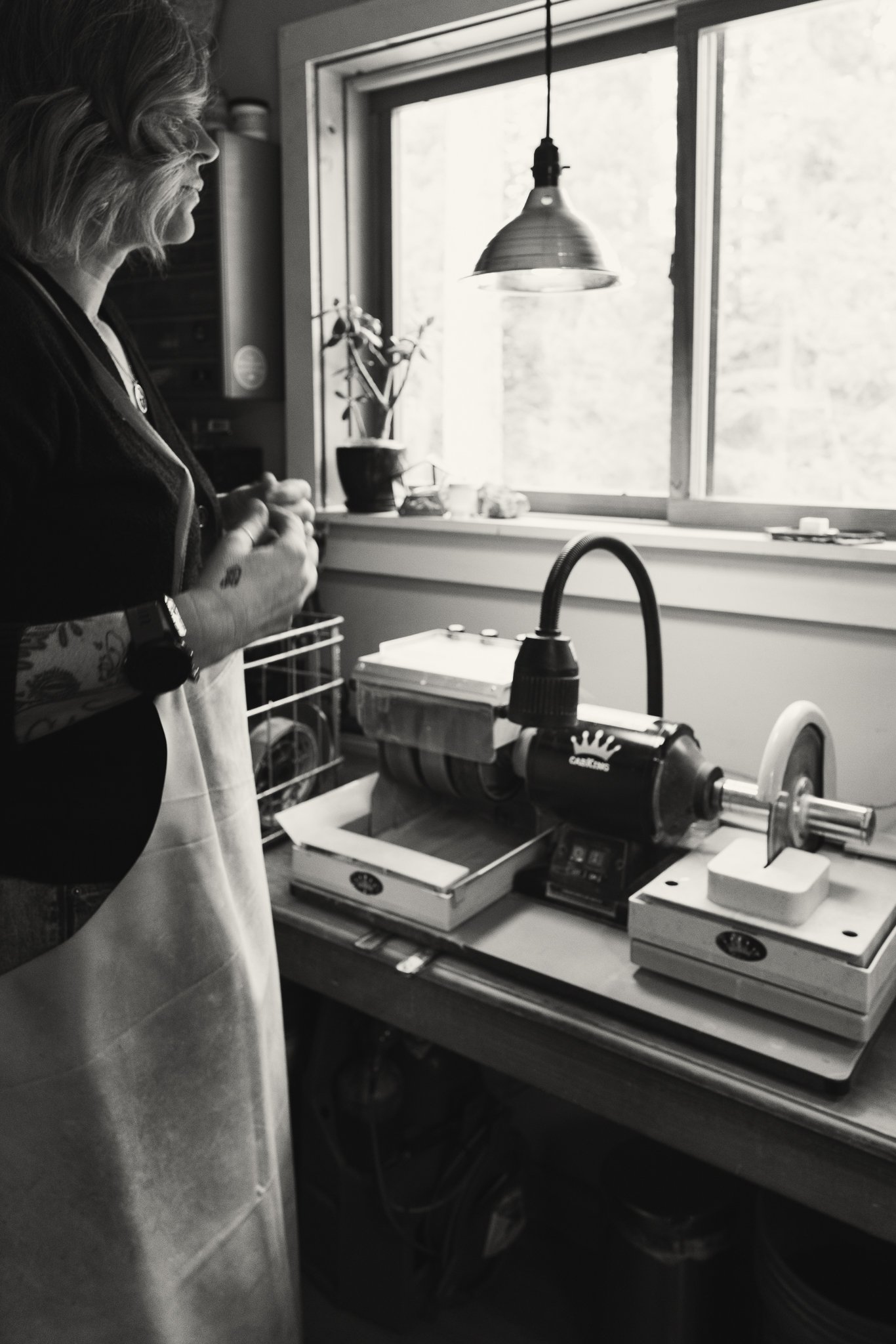 Person in workshop with polishing or grinding machine near a window.
