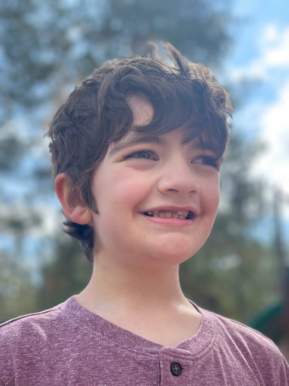A smiling child with ZMYND11-related disorder outdoors