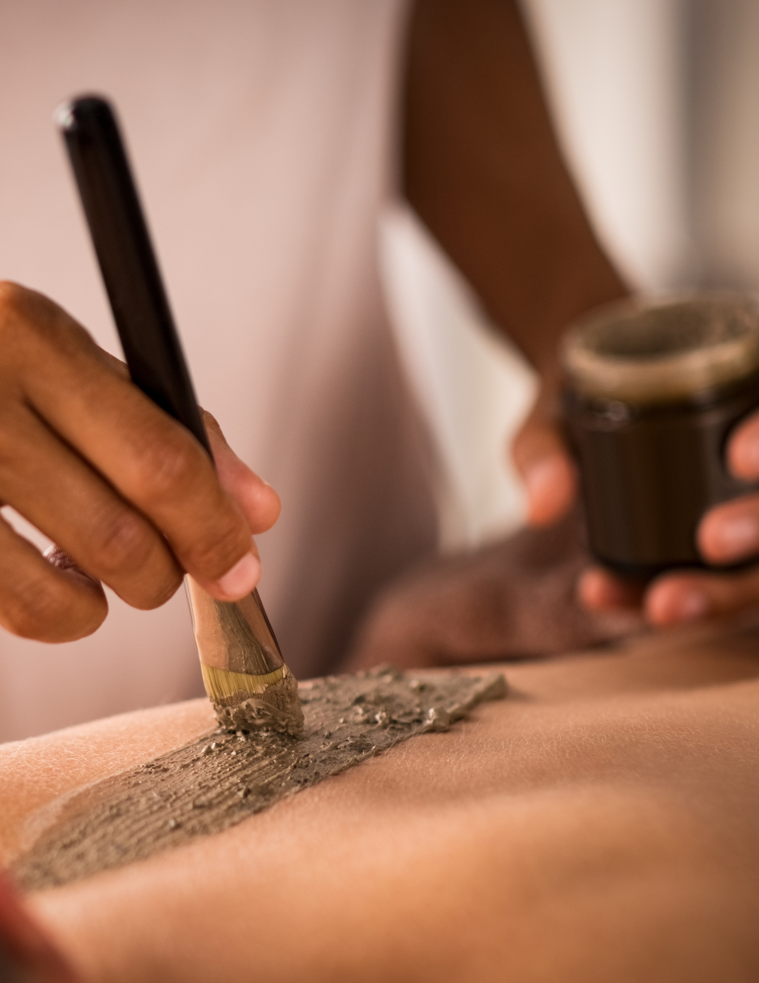 esthetician painting mud on client