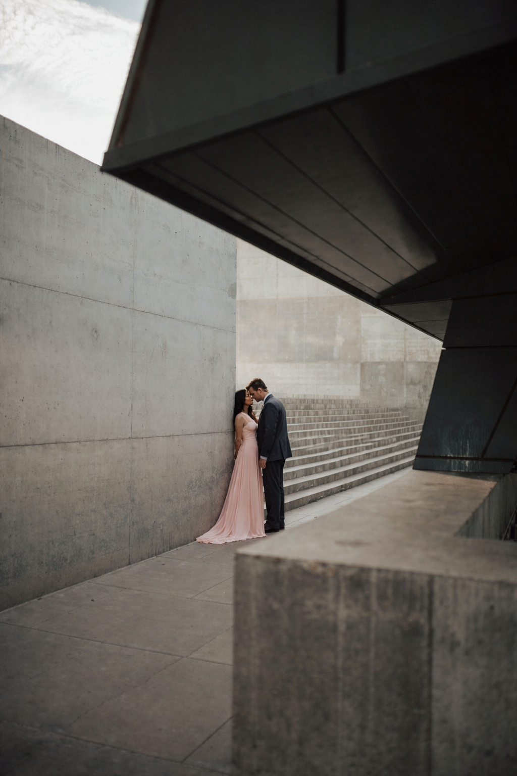 Engagement photographer Auckland — couple forehead to forehead urban setting by modern architecture — Wonderlens