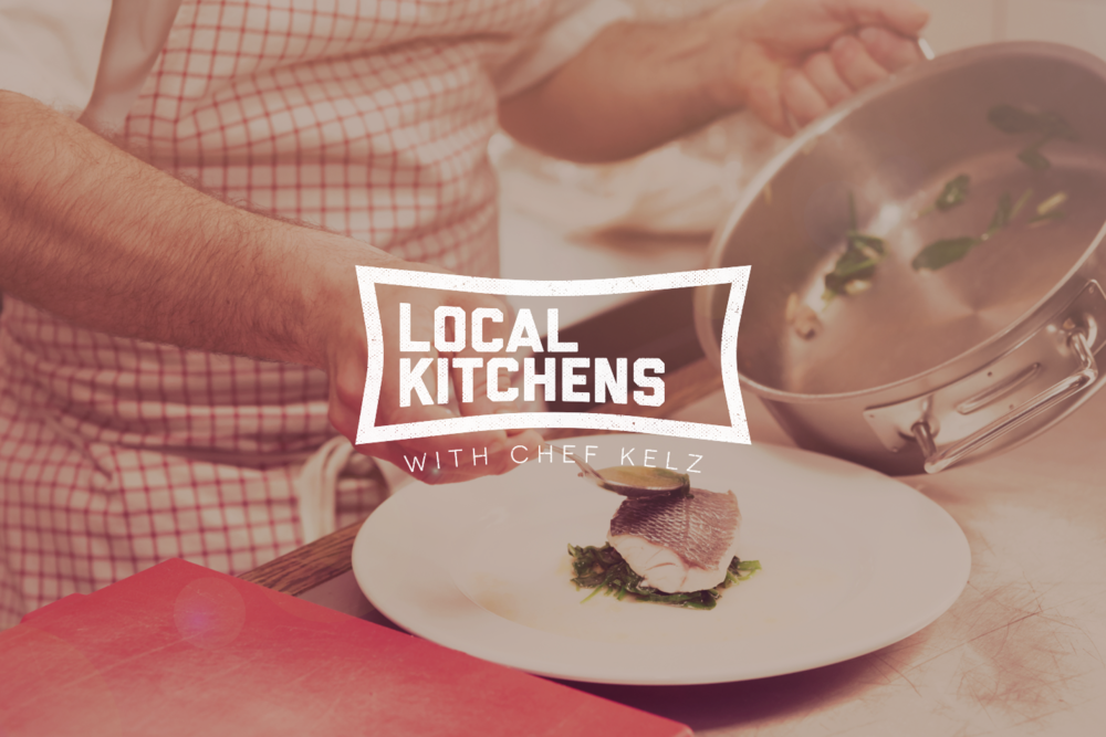 A chef garnishing a plated dish with a sauce, in a kitchen setting with a stainless steel pot and green herbs in the background.