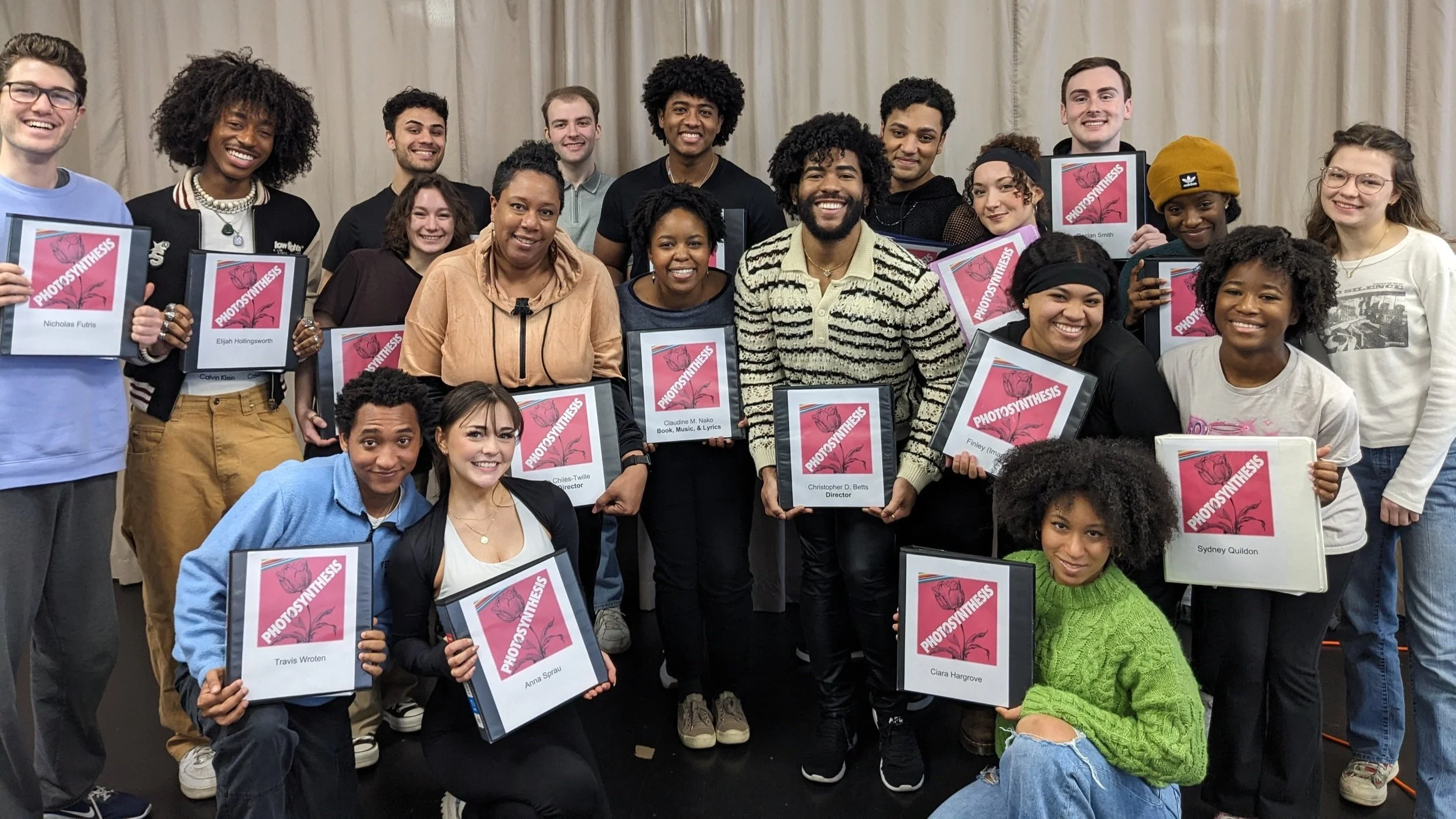 The cast and crew of Photosynthesis hold up their scripts following their first read through as part of Goodspeed Musicals' 2024 Festival of New Musicals