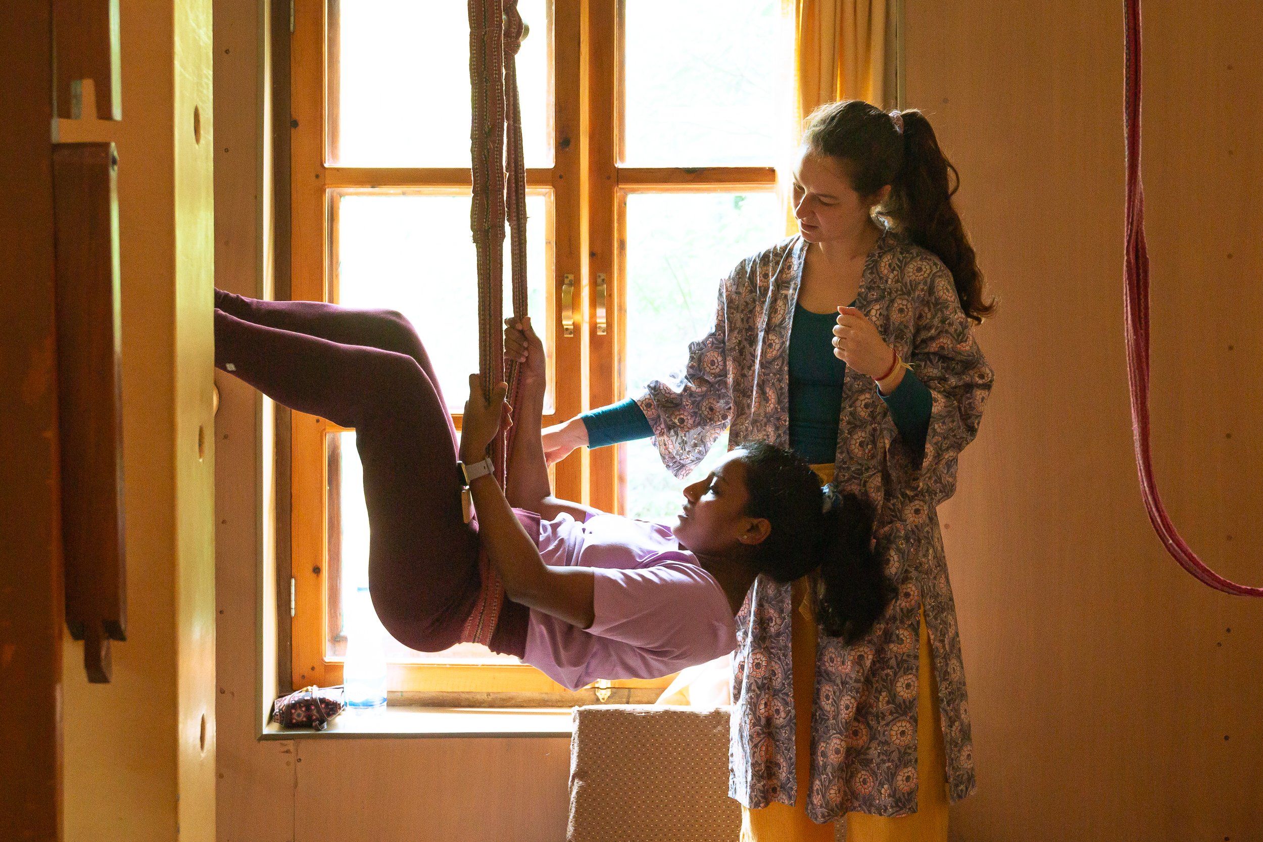 a yoga teacher showing a student how to use yoga props in a studio