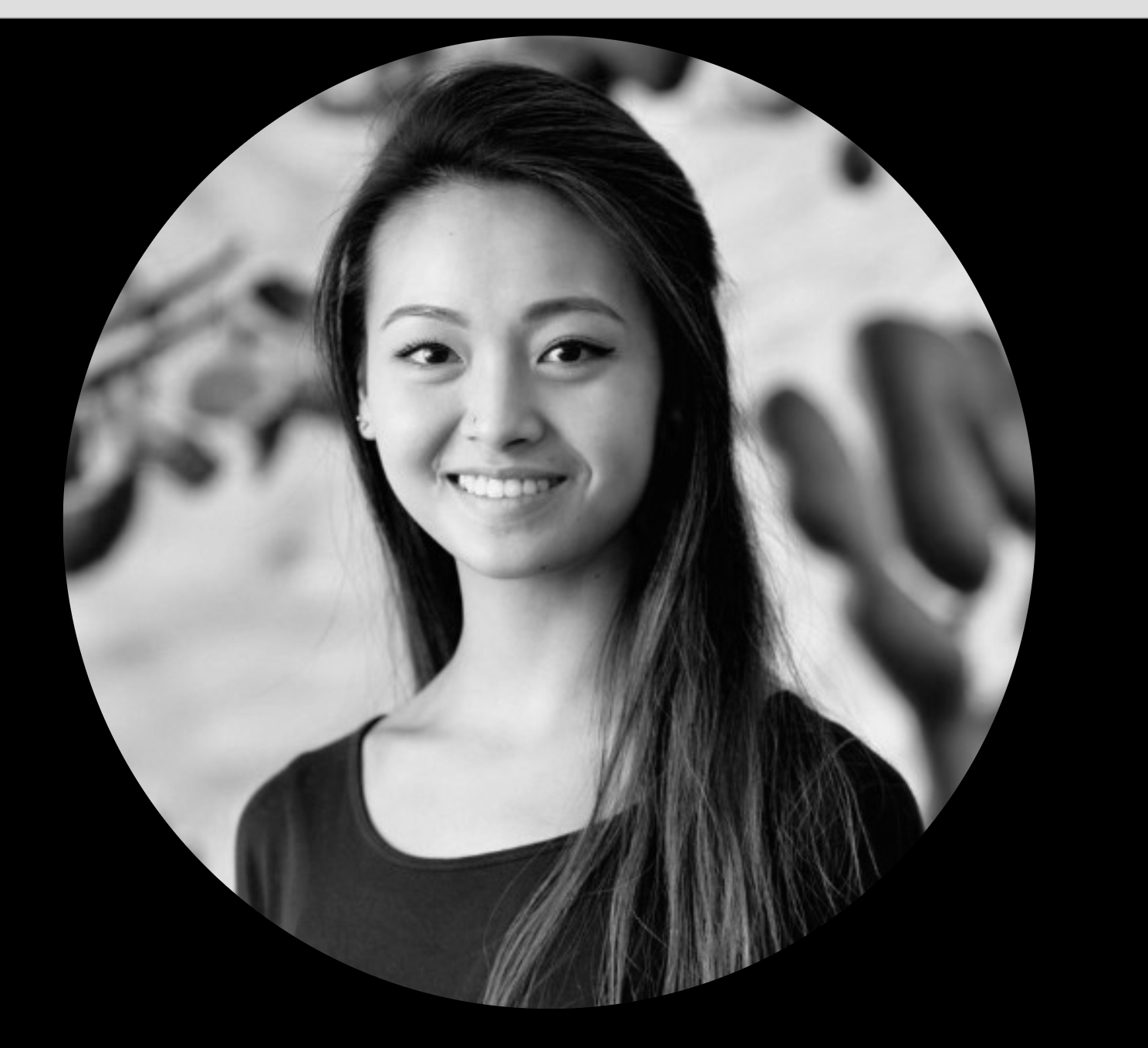Black and white photo of a young woman smiling and reaching towards the camera with her hand.