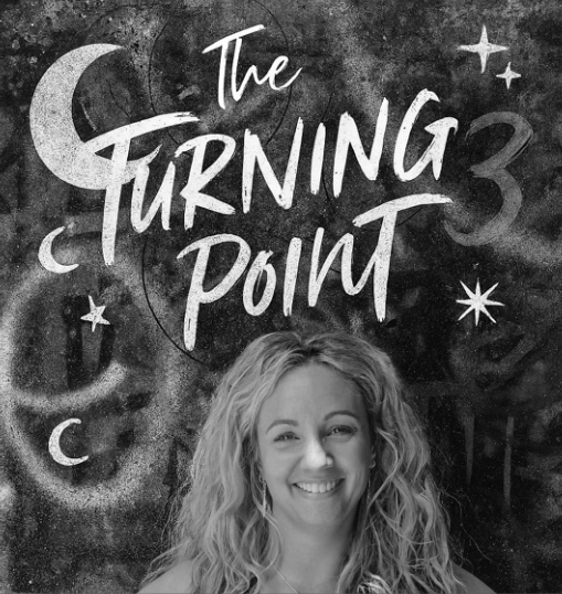 Black-and-white image of a smiling woman with curly hair, in front of a cosmic-themed mural with the text 'The Turning Point 3' and illustrations of planets, stars, and moons.