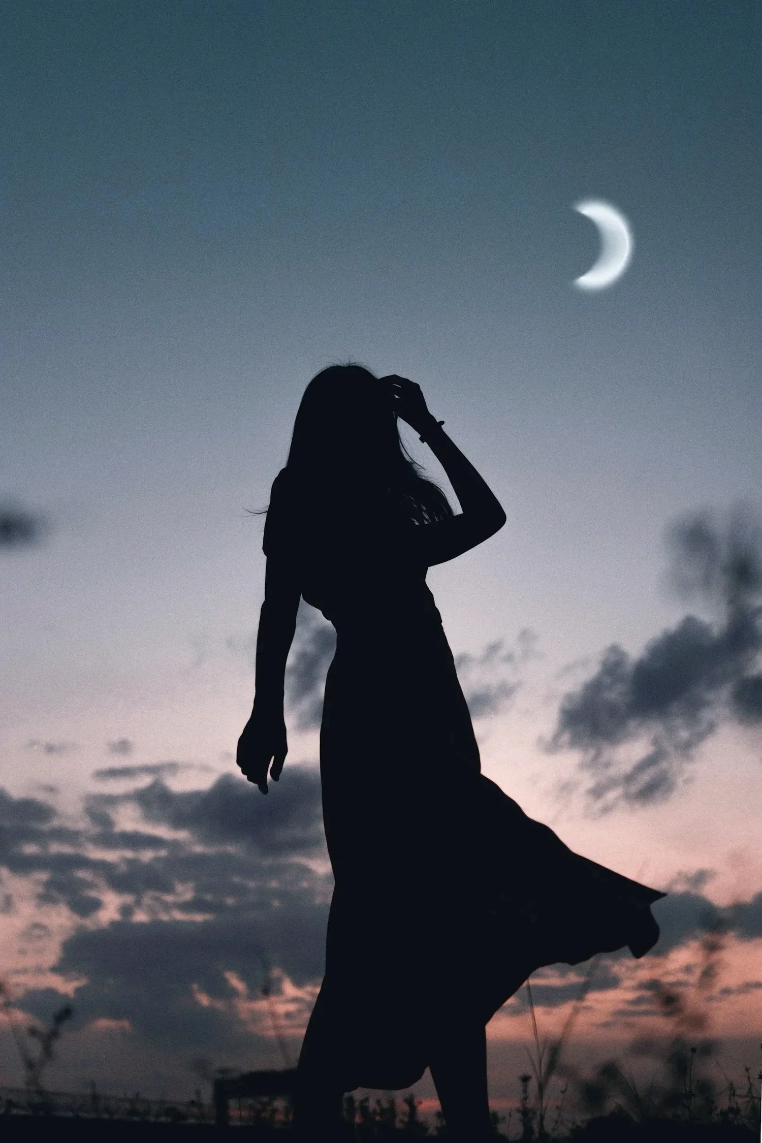 Silhouette of a woman at dusk with the moon