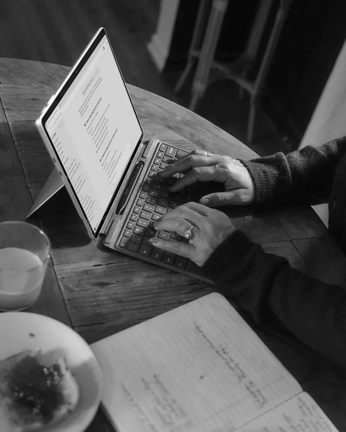 A woman at a laptop with orange juice and toast