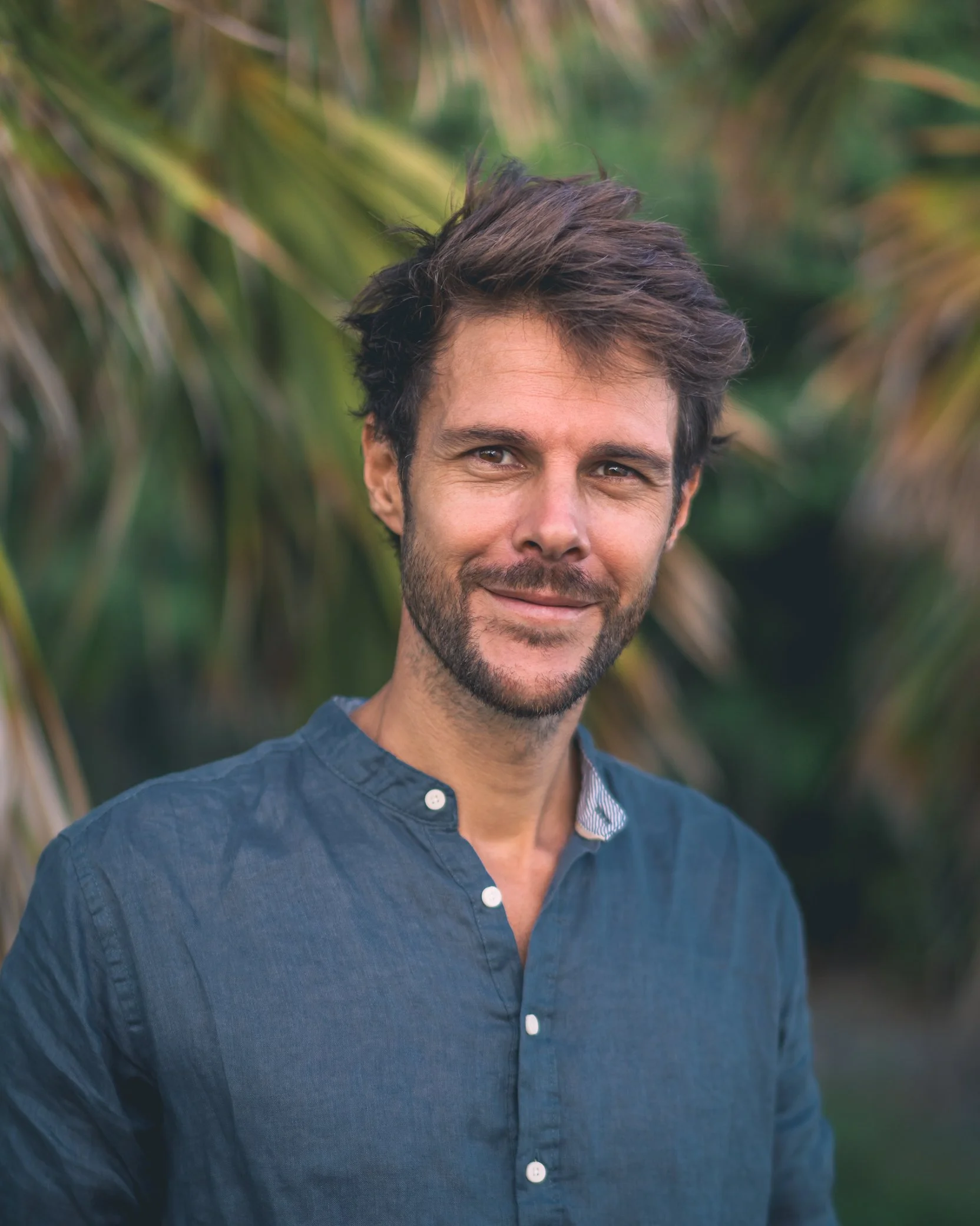 Portrait de Fabien Lefebvre, photographe en Martinique, souriant devant un feuillage