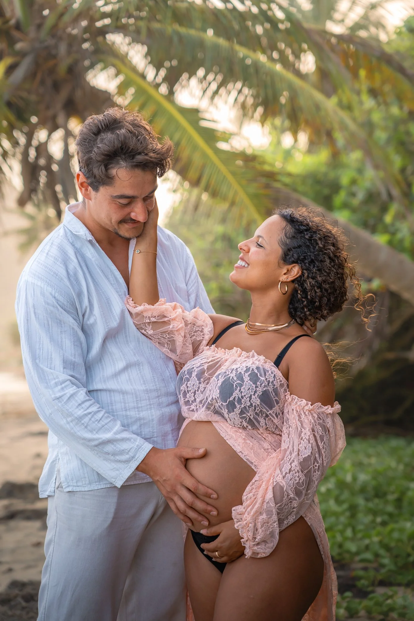 Couple lors d’une séance photo de grossesse à la plage du Diamant en Martinique, l’homme pose la main sur le ventre de sa compagne