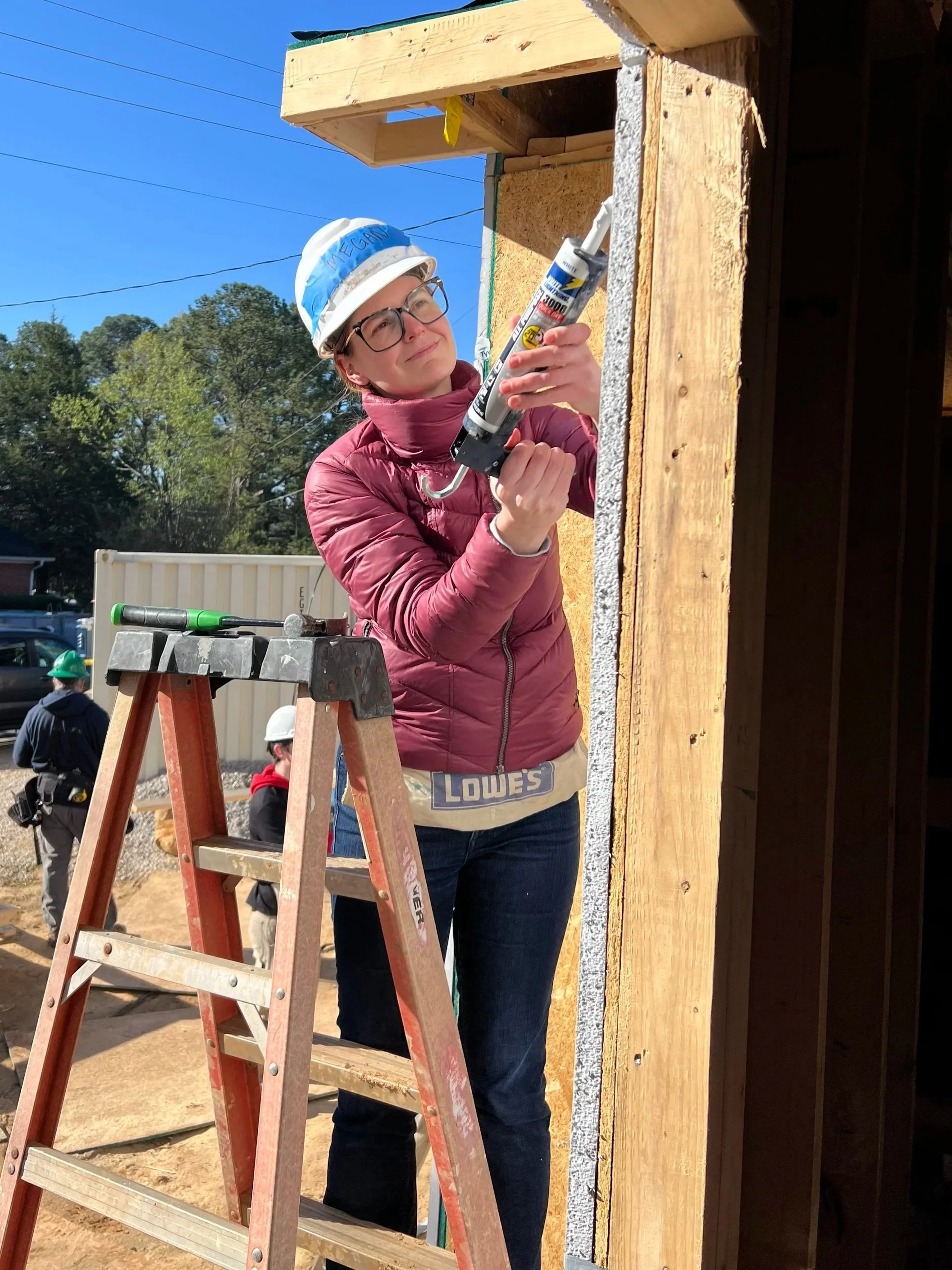 CM Patton using a caulking gun to install a window on a habitat for humanity home