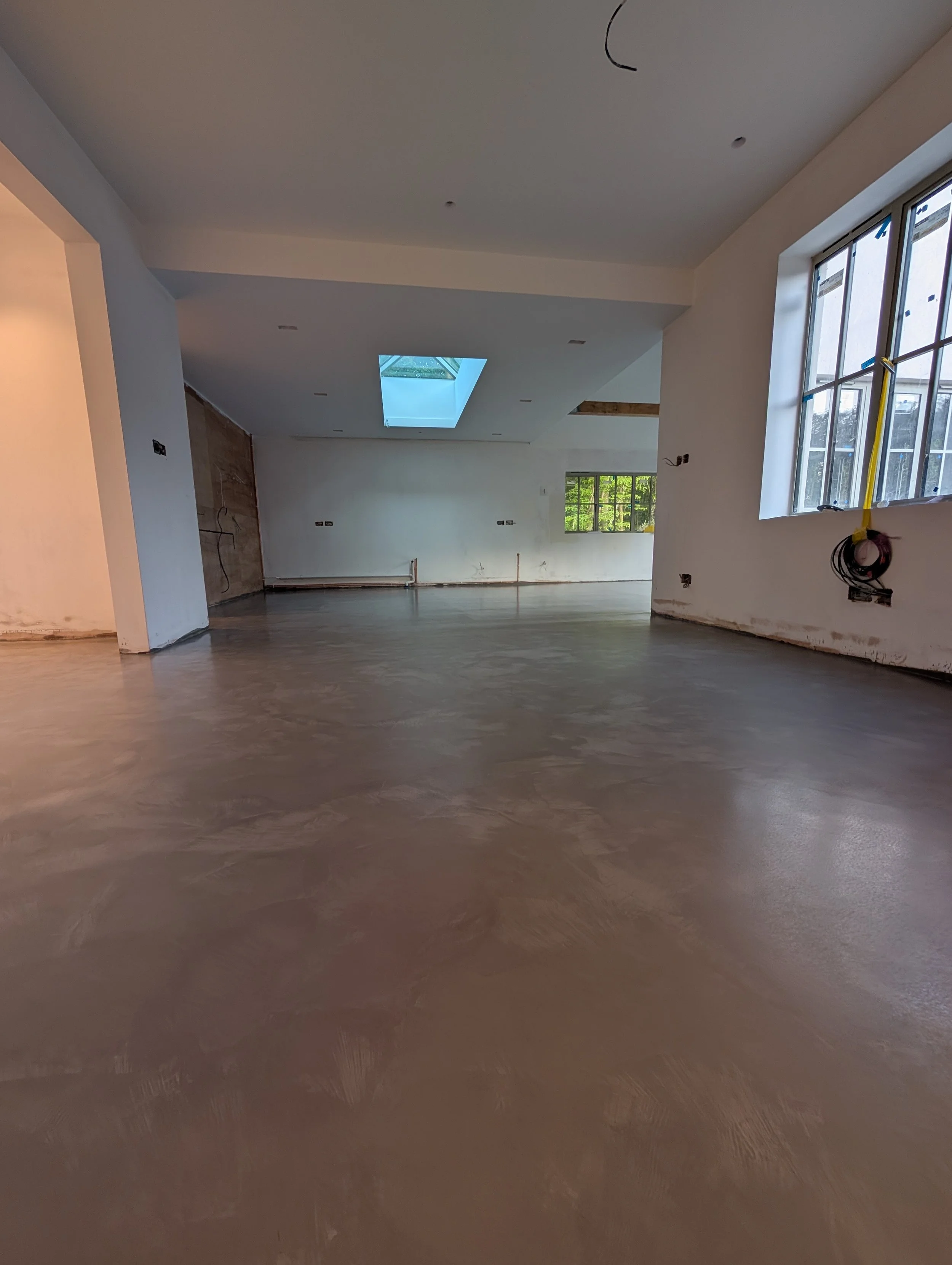 Interior of a house under construction with unfinished walls, a skylight in the ceiling, and windows, no furniture or decor.