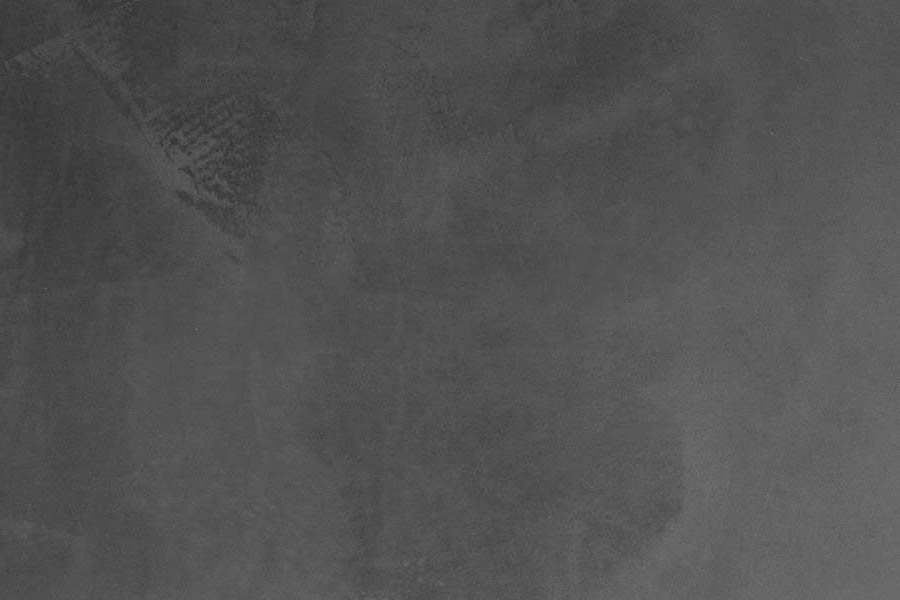 A dark, textured surface that appears to be a close-up of a black or dark gray object or material.